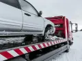 Srebrny samochód na czerwonym lawecie w zimowych warunkach.