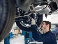 Mechanik w rękawiczkach naprawia podnośnik samochodowy.