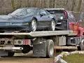 Czerwona laweta z zielonym Chevroletem Corvette na platformie.