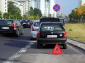 Czarny Opel z otwartą klapą bagażnika i trójkątem ostrzegawczym na autostradzie.