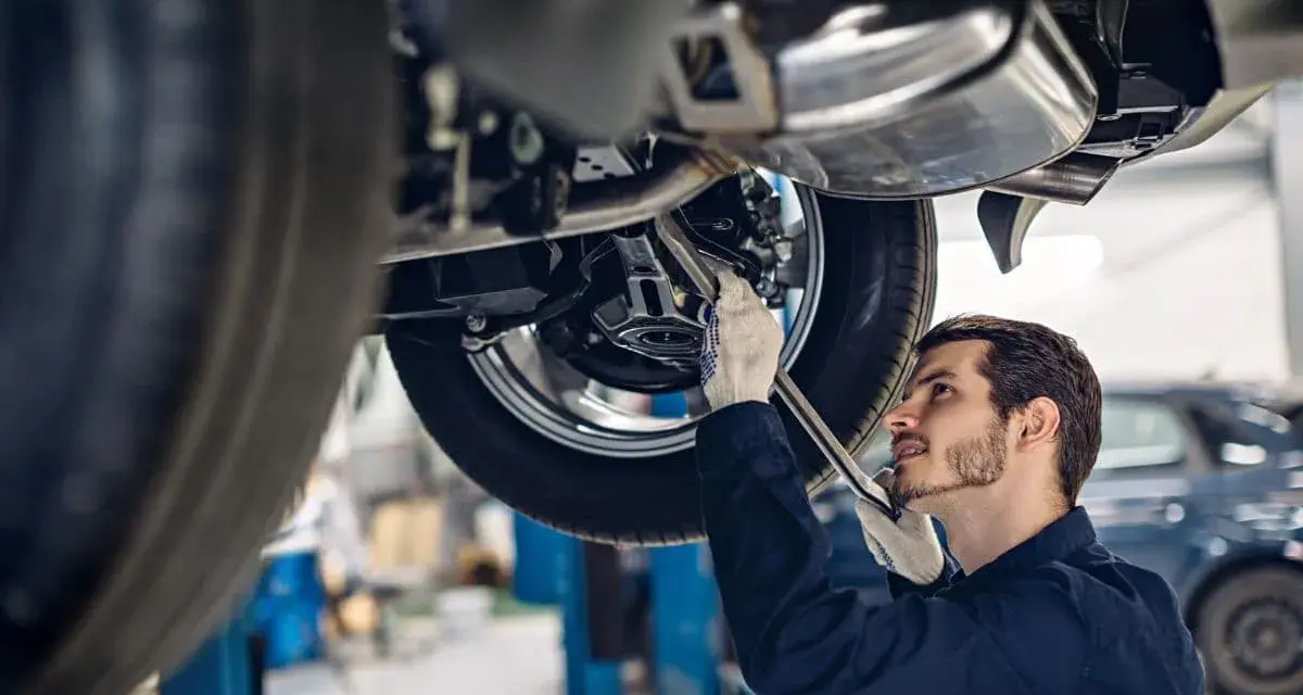 Mechanik w rękawiczkach naprawia podnośnik samochodowy.