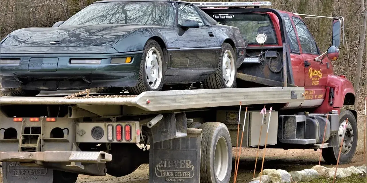 Czerwona laweta z zielonym Chevroletem Corvette na platformie.