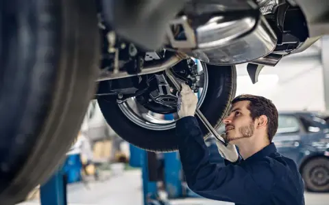 Mechanik w rękawiczkach naprawia podnośnik samochodowy.