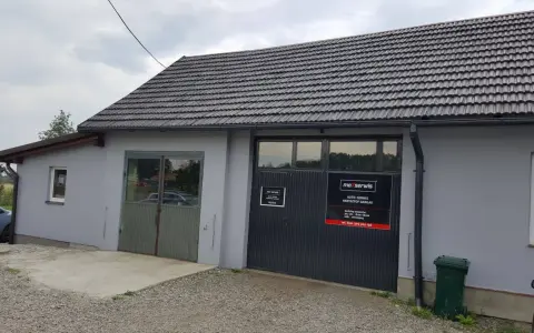 Budynek warsztatu samochodowego z szarym dachem i drzwiami garażowymi z logo "maxserwis".