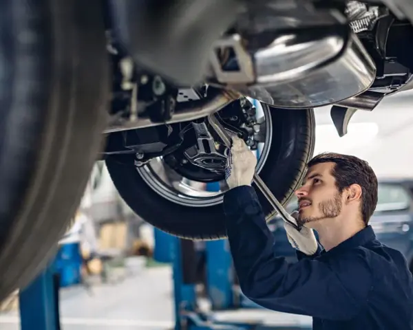 Mechanik w rękawiczkach naprawia podnośnik samochodowy.
