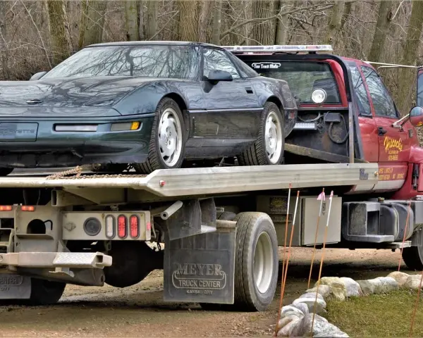 Czerwona laweta z zielonym Chevroletem Corvette na platformie.