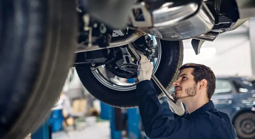Mechanik w rękawiczkach naprawia podnośnik samochodowy.