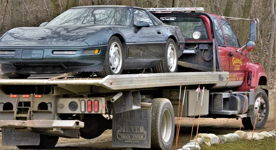 Czerwona laweta z zielonym Chevroletem Corvette na platformie.