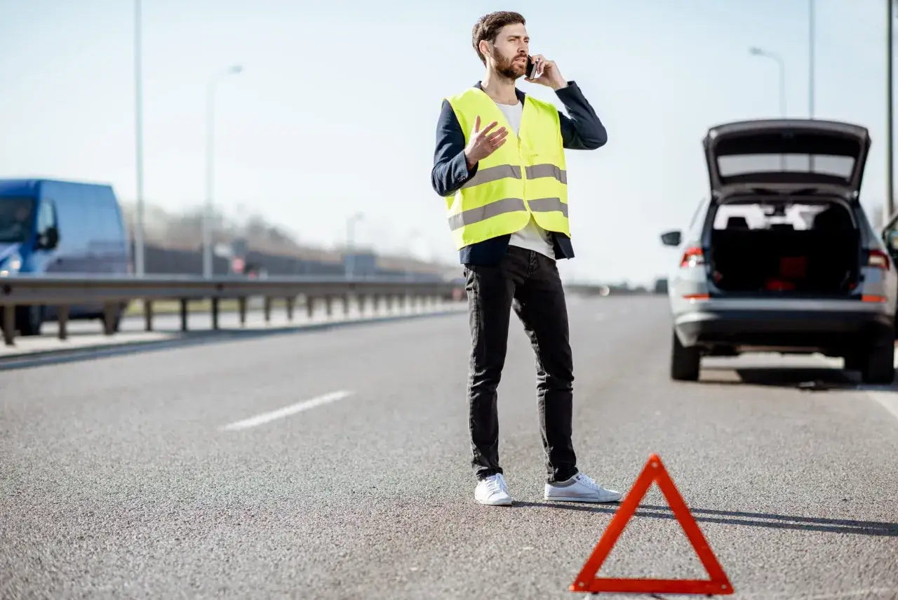 Holowanie pojazdu na autostradzie, laweta, trójkąt ostrzegawczy, kamizelka odblaskowa